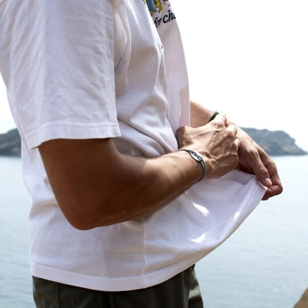 Photo d'un homme en T-Shirt blanc portant le bracelet argent vieilli BREVA sur fond de mer