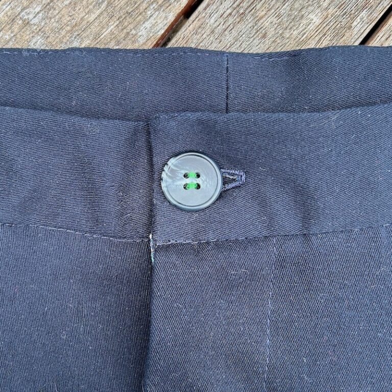 Gros plan sur le bouton avant du pantalon cousu de fil vert