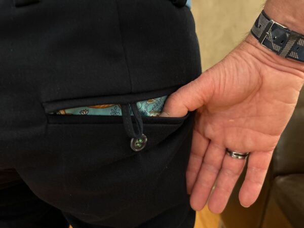 Photo de la poche arrière du pantalon Chino LUCAS Marine. Le pouce du mannequin est inséré dans la poche pour rendre visible le sac de poche imprimé